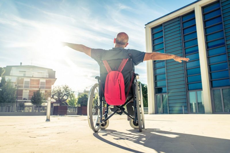man in a wheelchair outside by himself, an example of what is social distancing.
