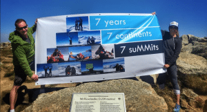 Kim Hess and her brother, Steven Hess, are shown holding up a celebratory banner for the completion of the Seven Summits.