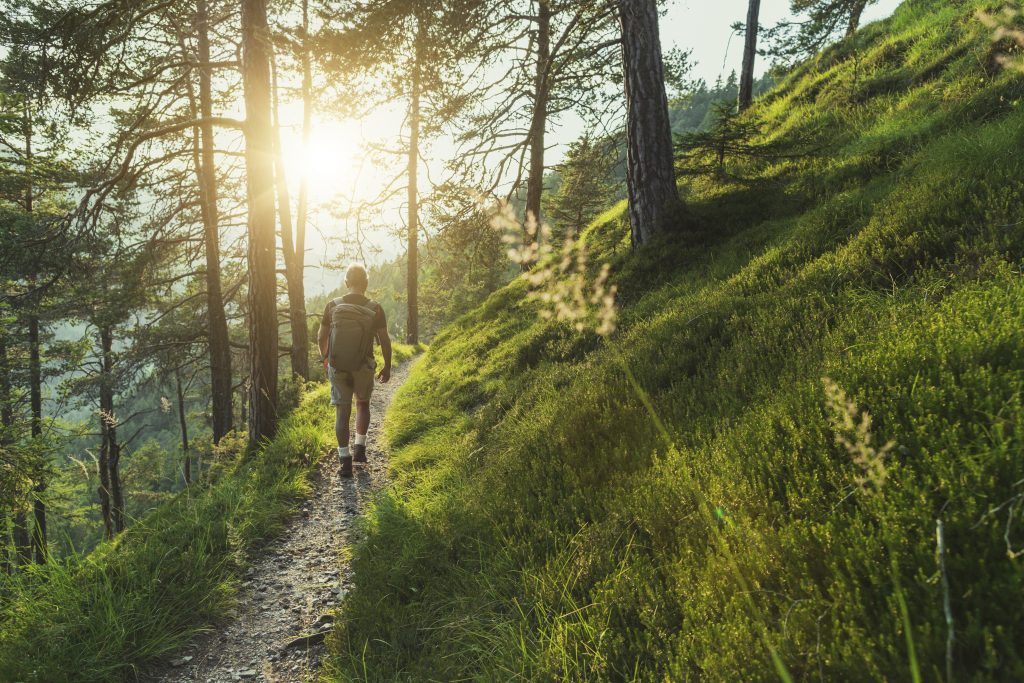 Foto de a man hiking alone on a trail in the mountains.
