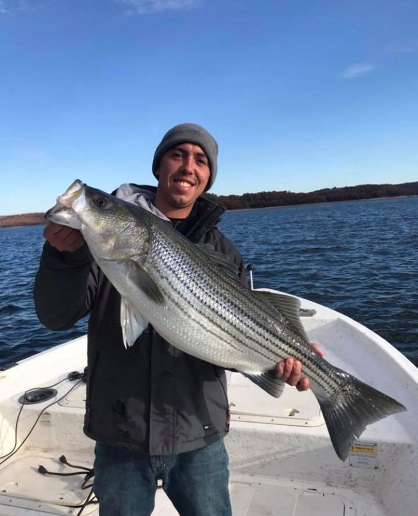 A young man on a boat with a big fish.