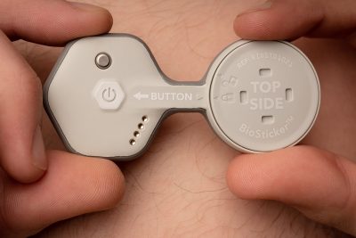 fingers hold a remote patient monitoring sticker