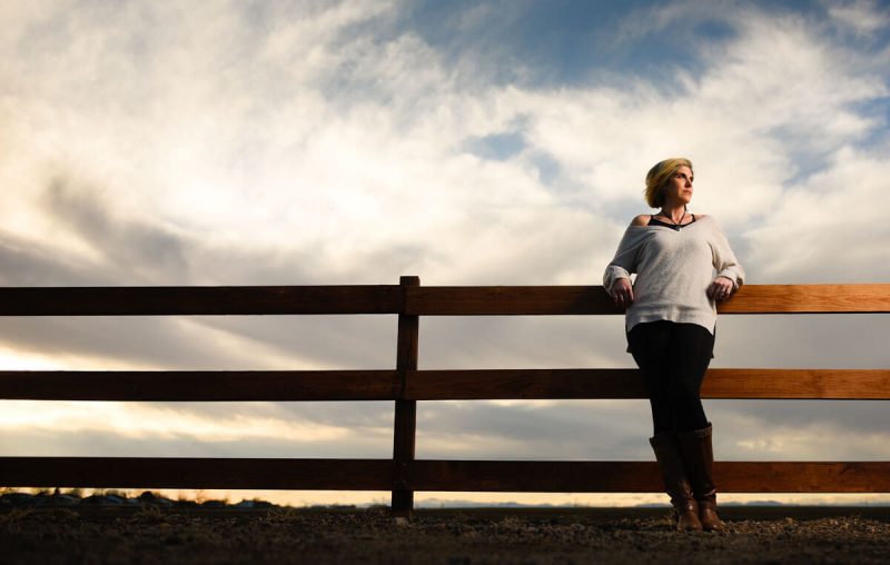woman stands in front of fence showing off her weight loss through a weight management program in primary care