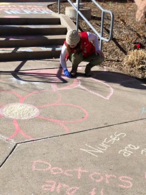 UCHealth volunteers chalk the walk outside of UCH.