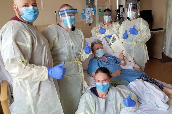 Staff at UCHealth surround Hakan Karan, a patient who recovered from COVID-19..
