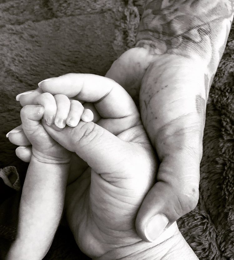 hands of mom, dad and baby in black and white.