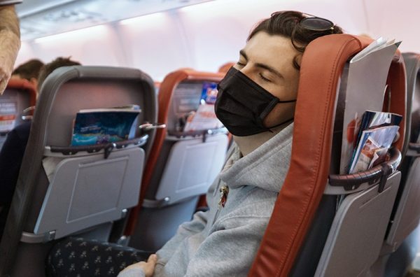 man sleeping with mask on a plane - airborne covid